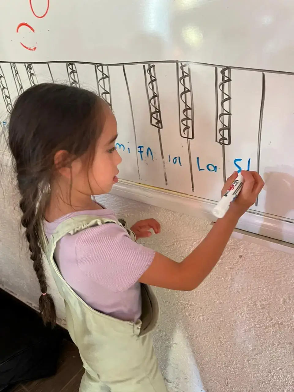 Niña de la Filarmonía Vallesana escribiendo notas musicales en un pizarrón